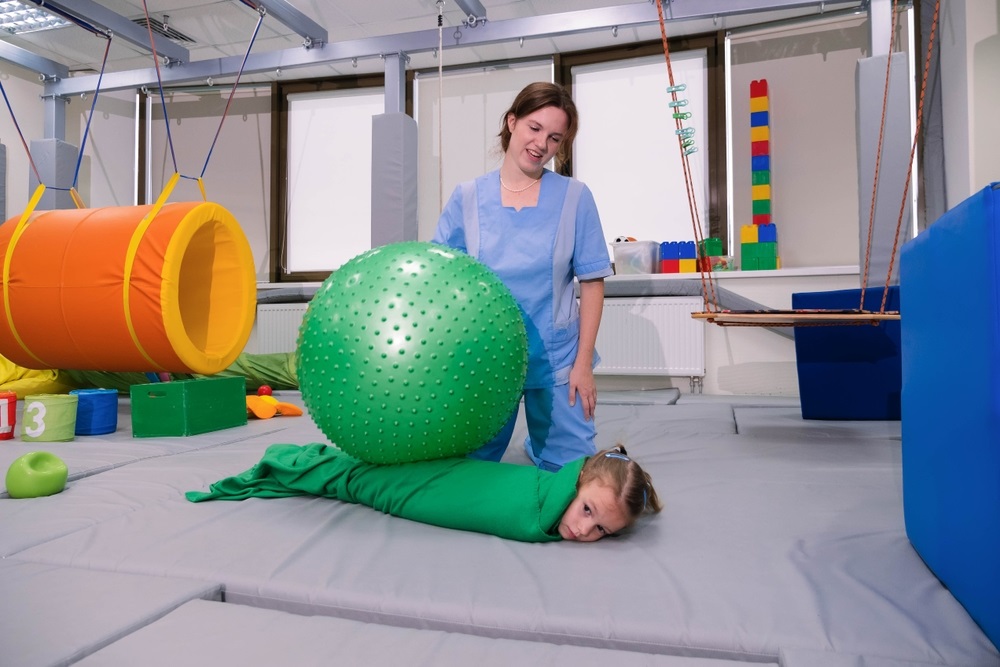 Physical,Therapist,Working,With,Little,Girl,In,Sensory,Room.,Exercising